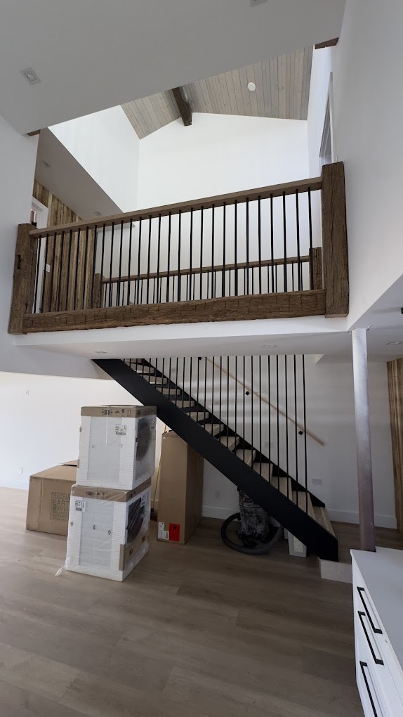 Modern interior staircase with reclaimed wood railing and metal spindles — built by Bulldog Construction.